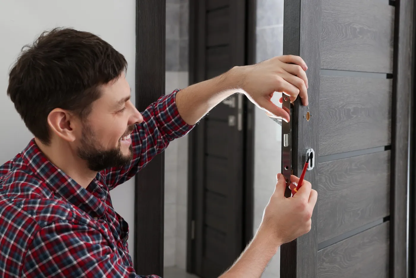 Artisan serrurier posant une serrure haute sûreté sur une porte sombre